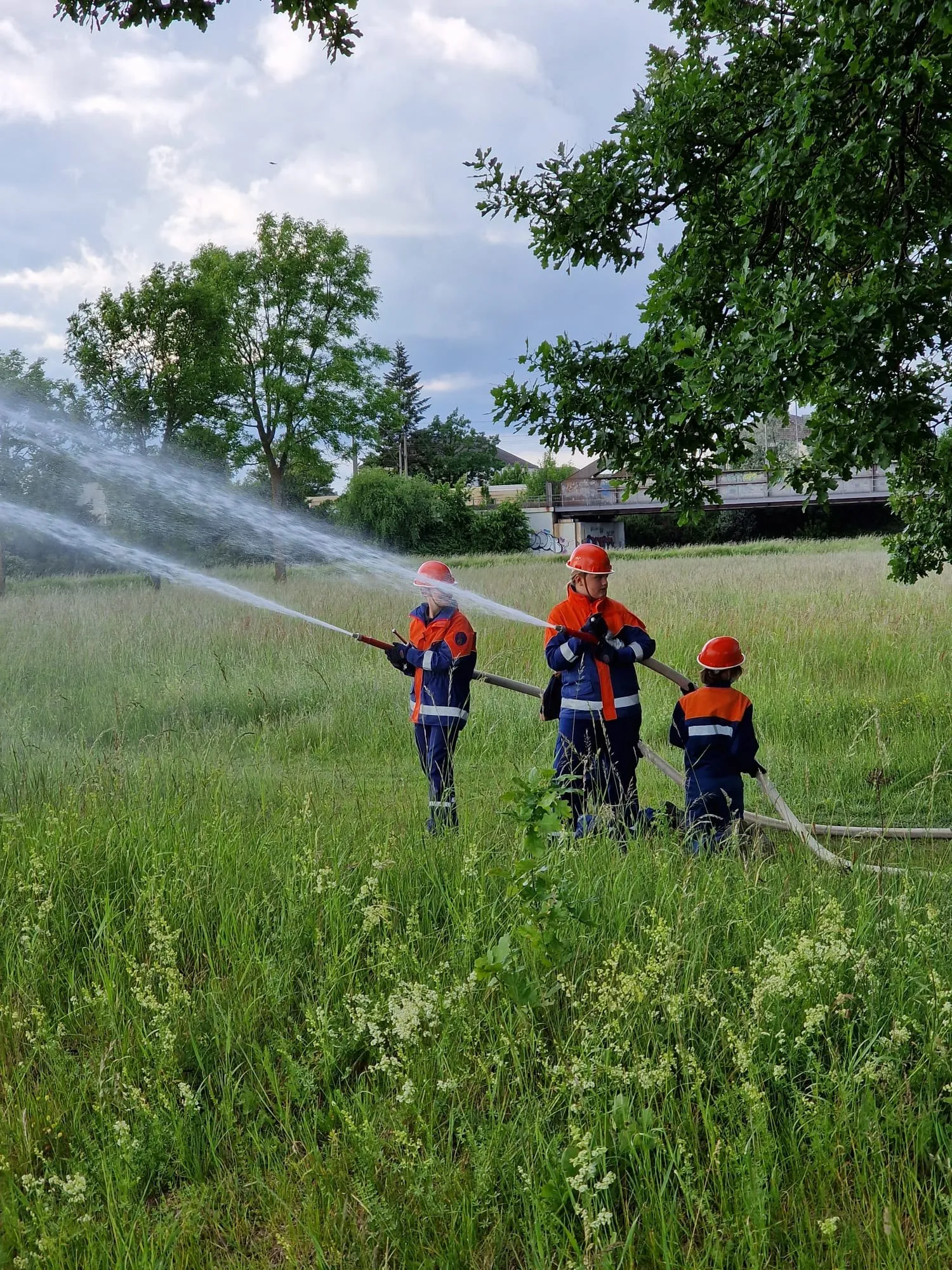 Jugendliche üben mit Strahlrohren auf einer Wiese