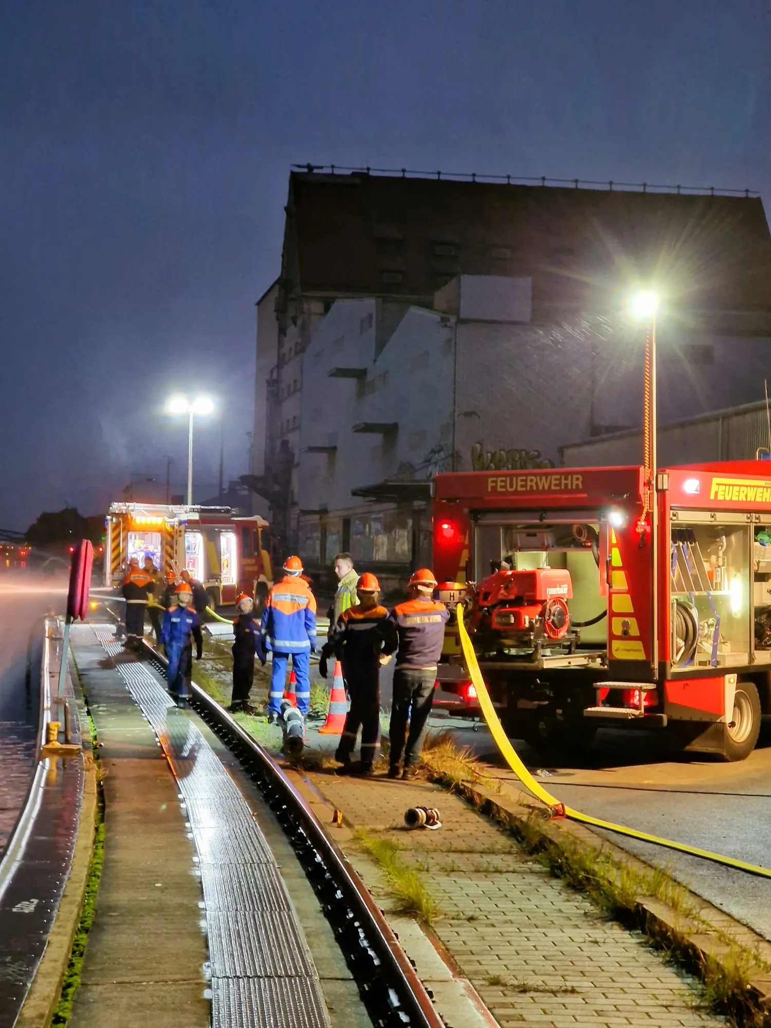 Jugendfeuerwehr bei der Wasserentnahme aus offenem Gewässer am Abend, daneben ein Feuerwehrfahrzeug